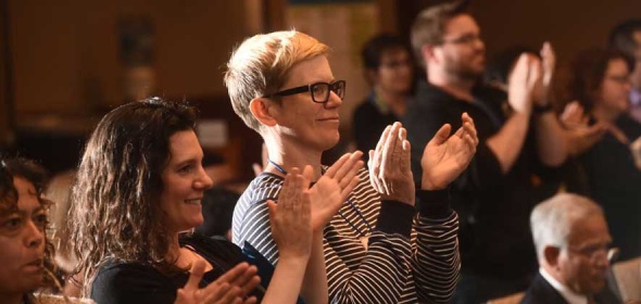 Photo of people in an audience standing and clapping