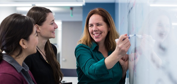 Photo of instructor with students at a whiteboard