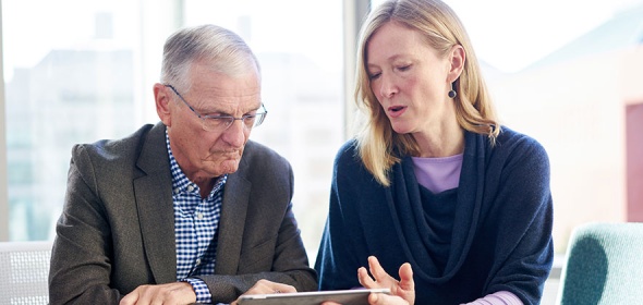Photo of two people conferring over a digital tablet