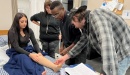 Photo of patient with leg injury being treated by three clinicians. Courtesy Kaiser Health News.